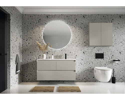 Modernt badrum med tvättställ, belyst spegel, väggskåp och toalett framför en vägg med stenmönster