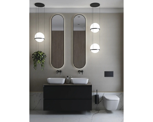 Modernt badrum med dubbla handfat, två speglar, vägghängd toalett och pendellampor.