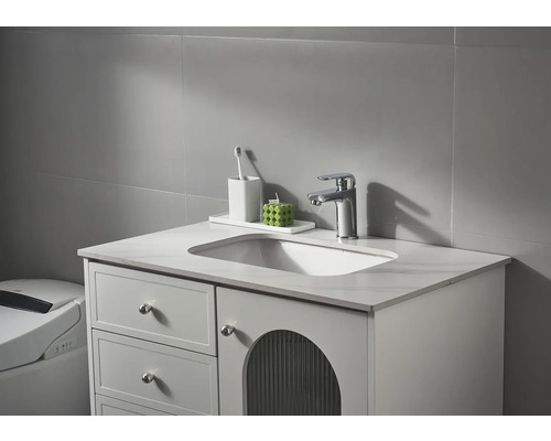 Tvättställsskåp med tvättställ, armatur och badrumstillbehör framför en grå vägg