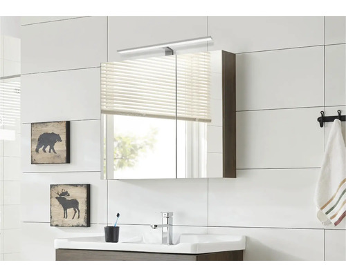 Modernt badrum med spegelskåp, tvättställ och väggdekoration