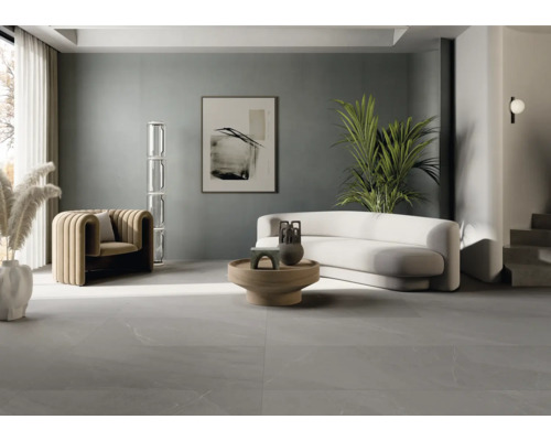 Ljust vardagsrum med fåtölj, soffa, bord och klinkergolv.