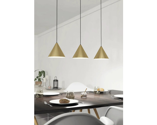 Tre guldiga hänglampor över ett matbord