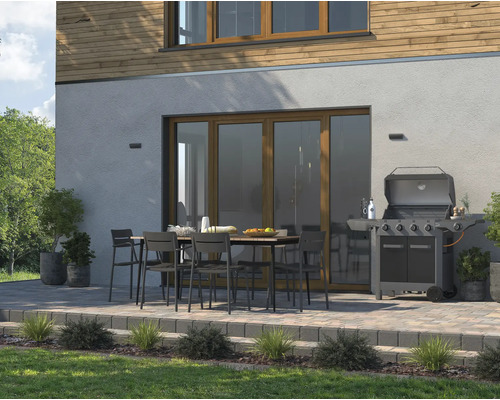 Uteplats med trädgårdsbord, stolar och gasolgrill vid huset