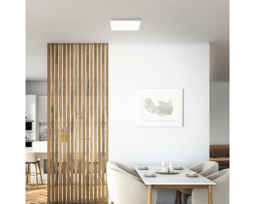 Ljus inredning med fyrkantig taklampa, träskärmvägg och matbord.