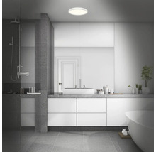 Modernt badrum med dusch, handfat, spegel, badkar och rund taklampa.