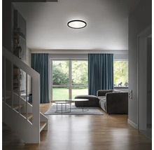 Vardagsrum med taklampa, soffgrupp och fönsterparti