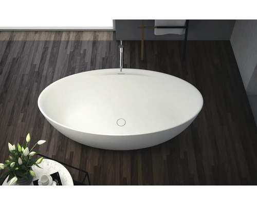 Fristående badkar i ett badrum med trägolv.