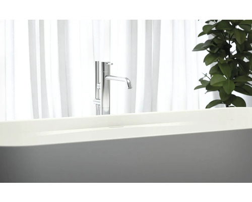 Fristående badkar med armatur framför ett fönster