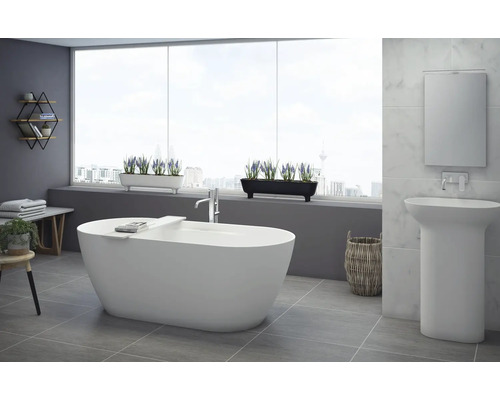 Modernt badrum med fristående badkar, tvättställ och dekorativa element för en ljus och vänlig atmosfär.