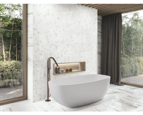 Badrum med fristående badkar, armatur, väggnisch och mosaikplattor