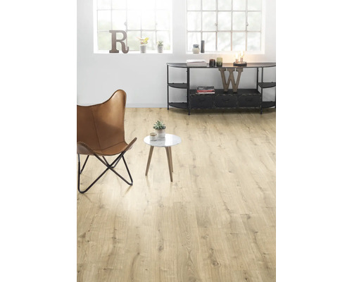 Ljust vardagsrum med trägolv, fåtölj och sidobord