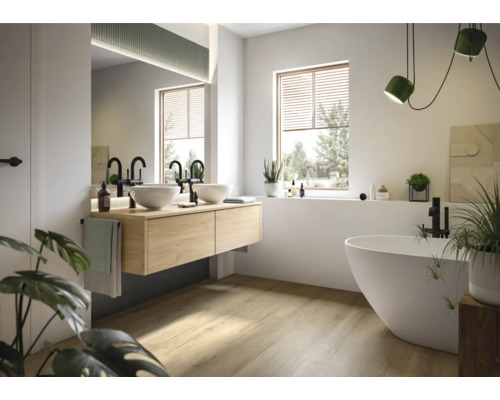 Ljust badrum med dubbla handfat, fristående badkar och fönster