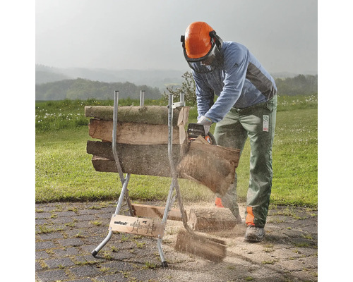 En person sågar ved med en motorsåg på en sågbock utomhus.