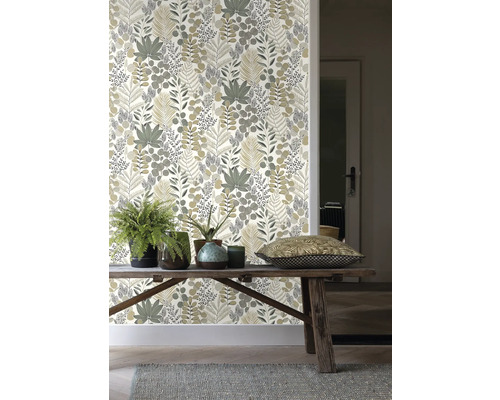 Rum med en vägg med tapet med bladmönster, ett träbord och växter