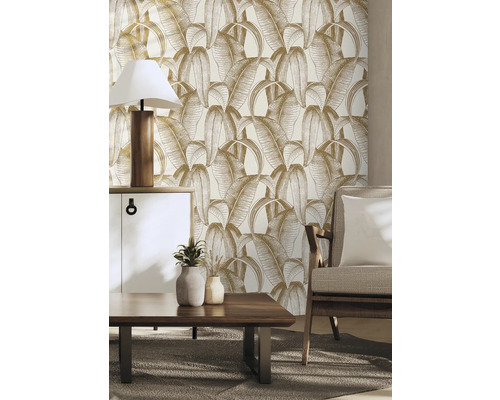 Vardagsrum med blad mönstrad tapet, byrå, bordslampa, soffbord och fåtölj