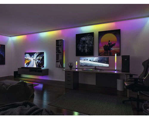 Modernt vardagsrum med spelhörna, upplyst med LED-lampor i tak, skåp och golvlampor.