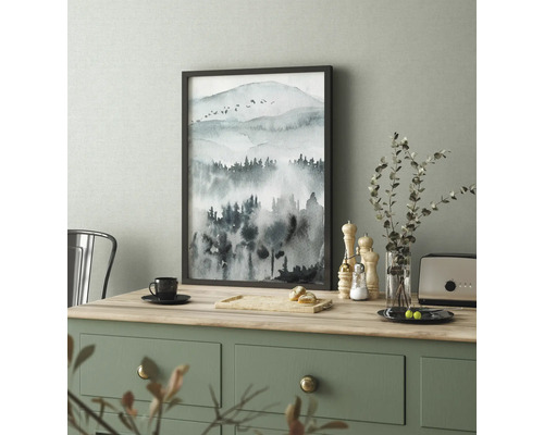 Inramad bild med akvarellmotiv av ett bergslandskap på ett bord