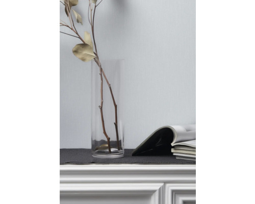 Dekorativa grenar i glasvas bredvid tidskrifter på byrå