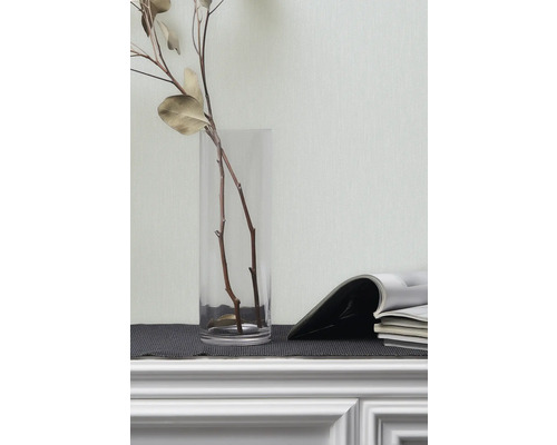 Dekorativa grenar i glasvas och tidskrifter på en hylla