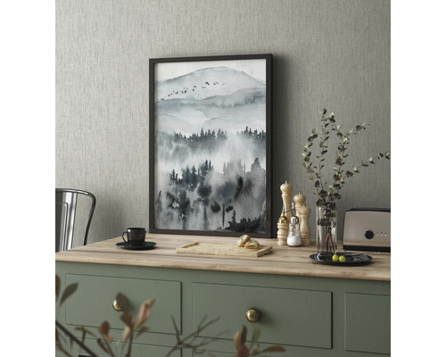 Dekorativ målning med bergmotiv i ram på ett köksbord.