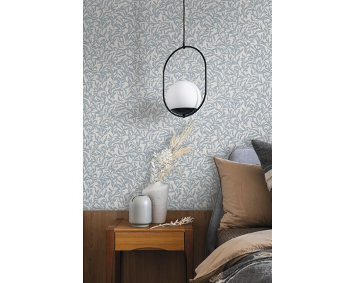 Sovrum med tapet med bladmönster, sängbord och lampa