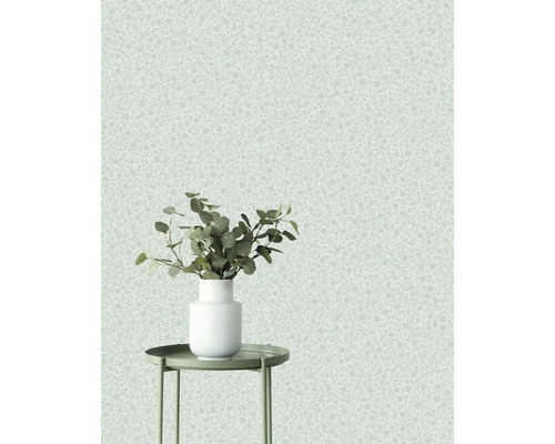 Dekorativ tapet med ett subtilt mönster och en vas med växter på ett sidobord.