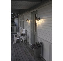 Veranda med två väggmonterade utomhuslampor, stol, bord och planteringslåda