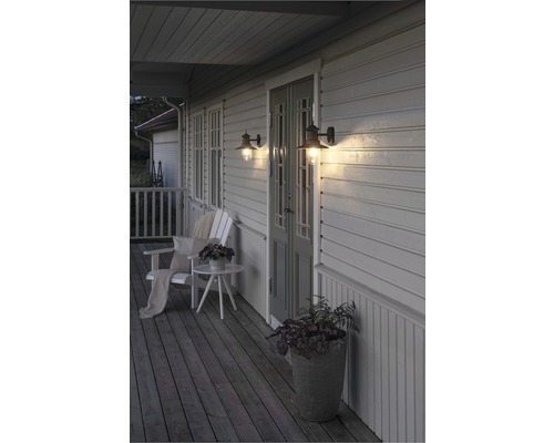 Veranda med två väggmonterade utomhuslampor, stol, bord och planteringslåda
