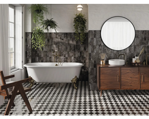 Badrum med badkar, handfat, spegel, träskåp och svartvitt schackrutigt klinkergolv.