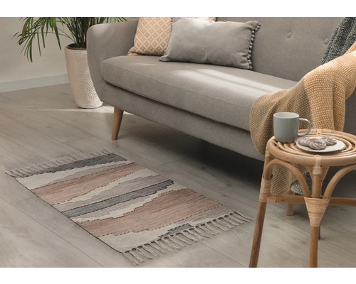 Vardagsrum med soffa, krukväxt och mönstrad matta