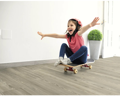 Flicka med hjälm och skateboard på ljust trägolv