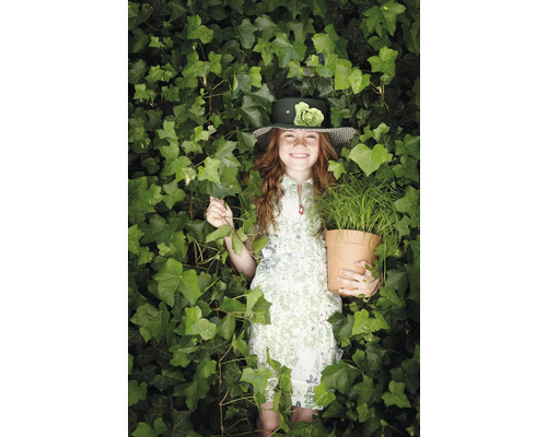 Flicka med hatt och blomkruka mitt i murgrönan