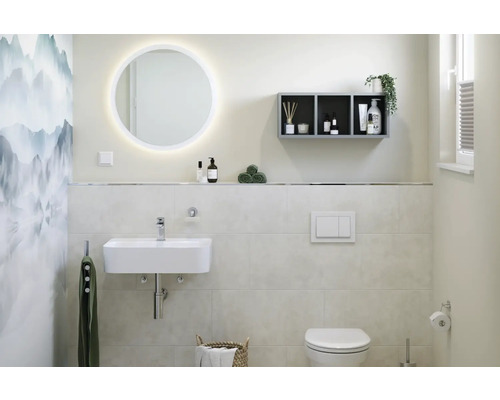 Badrum med tvättställ, belyst spegel, hylla och toalett.