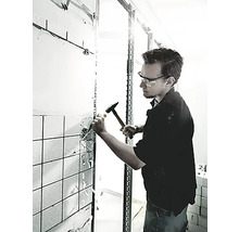 En man använder en hammare och mejsel för att ta bort kakel från en vägg.