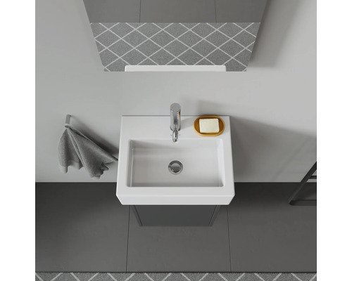 Toppvy av ett badrum med handfat, kran, tvålkopp och handdukshängare