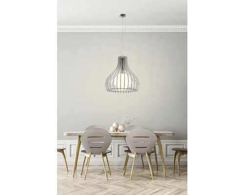 Matsal med pendellampa i metall ovanför ett träbord med stolar