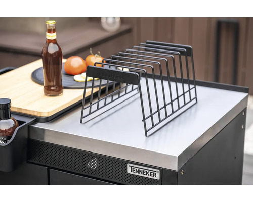 Metallförvaringsgaller på grillstation med flaska, tomater och skärbräda