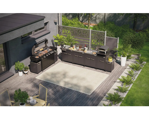 Vy från ovan av ett utekök med grill, diskho, pizzaugn och arbetsytor på en träaltan