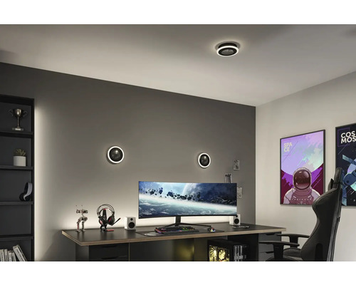 Modernt spelrum med skrivbord, dator och runda vägglampor.