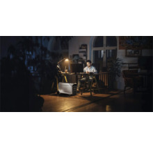 Man som arbetar vid skrivbord med bärbart kraftverk i rummet