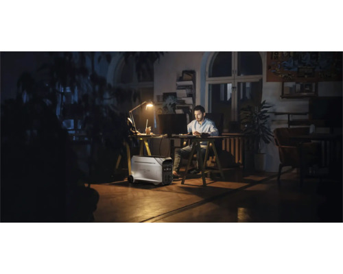 Man som arbetar vid skrivbord med bärbart kraftverk i rummet