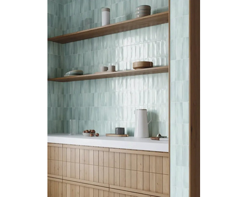 Närbild av en interiör med kökskakel, hyllor och köksredskap