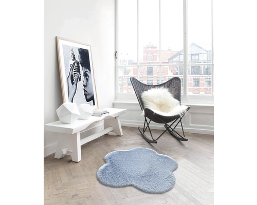 Vardagsrum med molnformad matta, bänk, fåtölj och inramad affisch