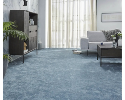 Vardagsrum med blå heltäckningsmatta, soffa, bord och skåp