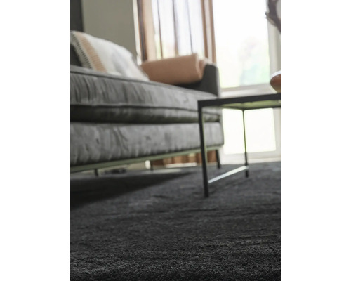 Närbild av en grå matta i ett vardagsrum med soffa och bord