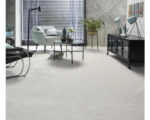 Ljust vardagsrum med heltäckningsmatta, fåtölj, bord och dekoration