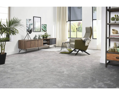 Vardagsrum med heltäckningsmatta, skänk, fåtölj och krukväxter för en mysig atmosfär.