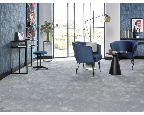 Vardagsrum med grå heltäckningsmatta, blå fåtöljer och svarta möbler framför fönsterparti