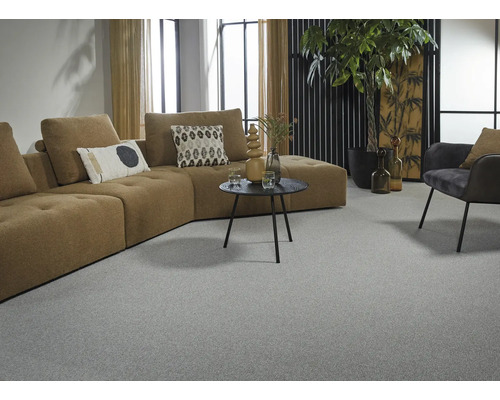 Vardagsrum med grå heltäckningsmatta, brun hörnsoffa och dekorationer