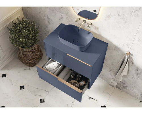 Modernt badrum med blått underskåp, tvättställsskål och öppen låda för förvaring av badrumsartiklar.